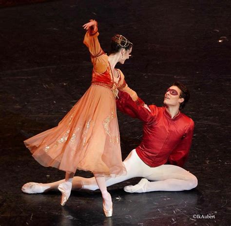 A Man And Woman In Ballet Clothes On The Floor With Their Arms Around