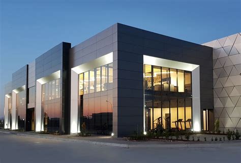 An Office Building Lit Up At Night With Lights On The Front And Side Of It