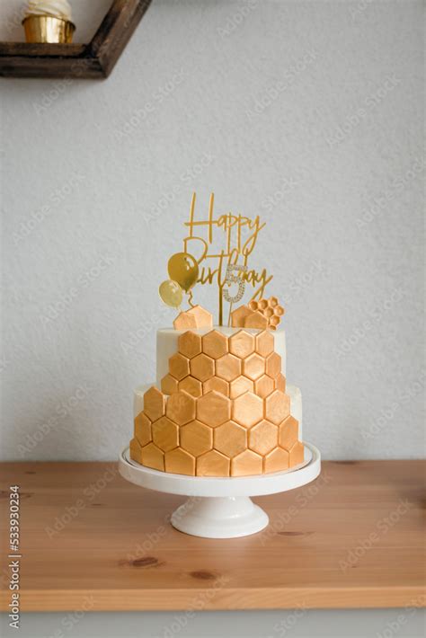 Making a sweet table for a birthday. Cake with honeycombs, golden ...