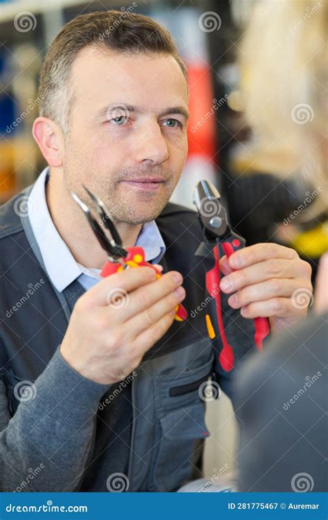 Shopassistent Zeigt Dem Kunden Zwei Typen Von Zangen An Stockbild