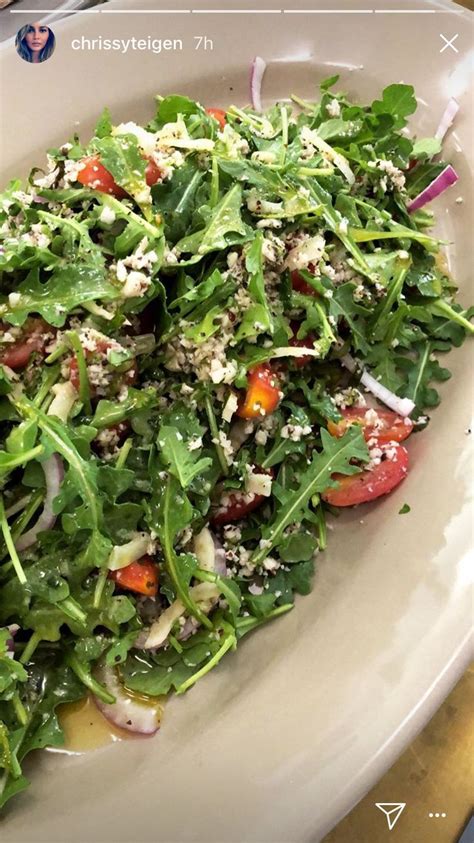 A White Bowl Filled With Salad On Top Of A Table