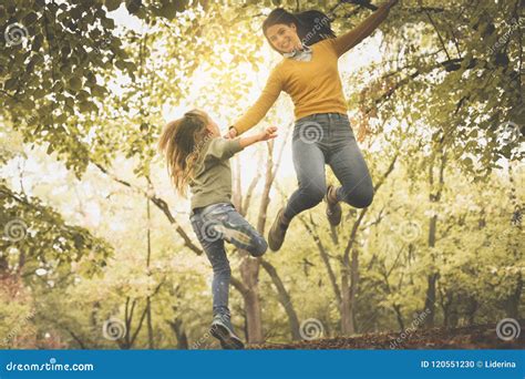 Mother And Daughter On Meadow Mother And Daughter Jumping Together