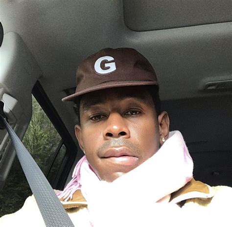 A Man Sitting In The Passenger Seat Of A Car Wearing A Hat And Scarf On