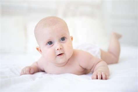 Premium Photo | A healthy happy cute baby lies on his stomach and looks ...