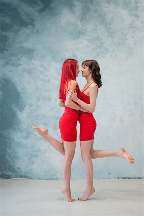 Full Length Portrait Of Two Tenderly Embracing Women Dressed In