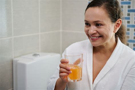 Middleaged Woman In Bathrobe Holds A Glass Of Water With Effervescent