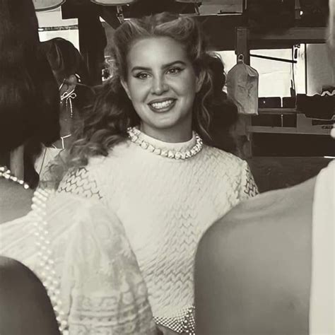 A Black And White Photo Of A Woman In Pearls Smiling At The Camera With