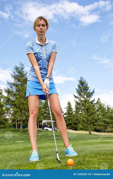 A Beautiful Woman While Playing Golf Is Getting Ready To Hit The Ball