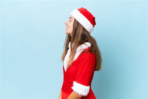 Jovem mulher caucasiana vestida como mamãe noel isolada em fundo azul