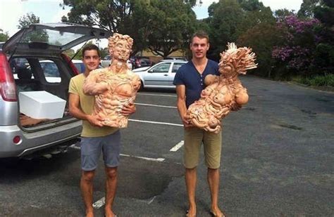 Two Men Standing In The Parking Lot Holding Sculptures