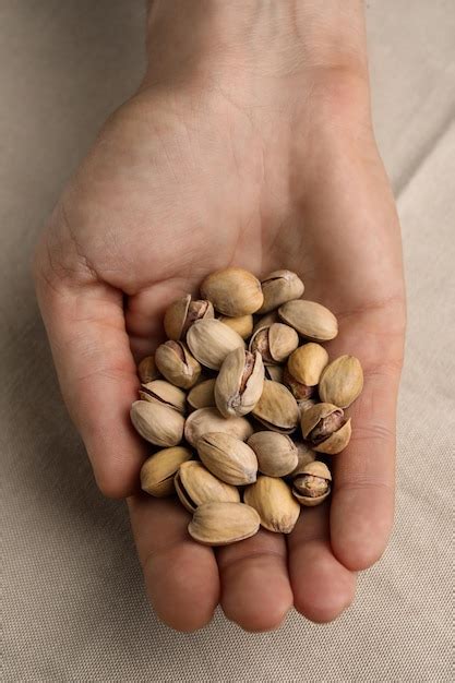 Premium Photo Woman Holding Tasty Roasted Pistachio Nuts At Table Top