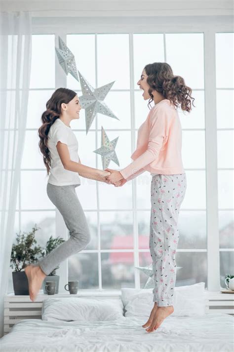 Mom And Daughter Jumping On Bed Holding Hands Stock Image Image Of