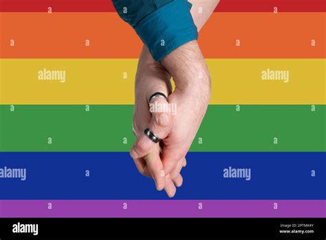 Homosexual Couple Hands Into Each Other On Rainbow Flag Background