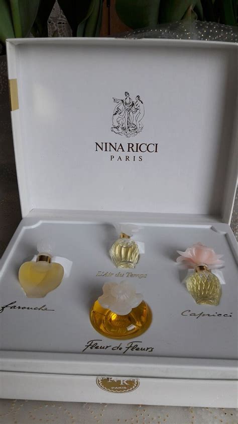 Three Pieces Of Perfume In A White Box With Gold Trimmings On The Sides