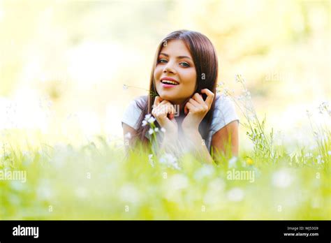 Beautiful young woman lying on grass with flowers Stock Photo - Alamy