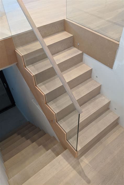 The Stairs Are Made Of Wood And Have Glass Railings