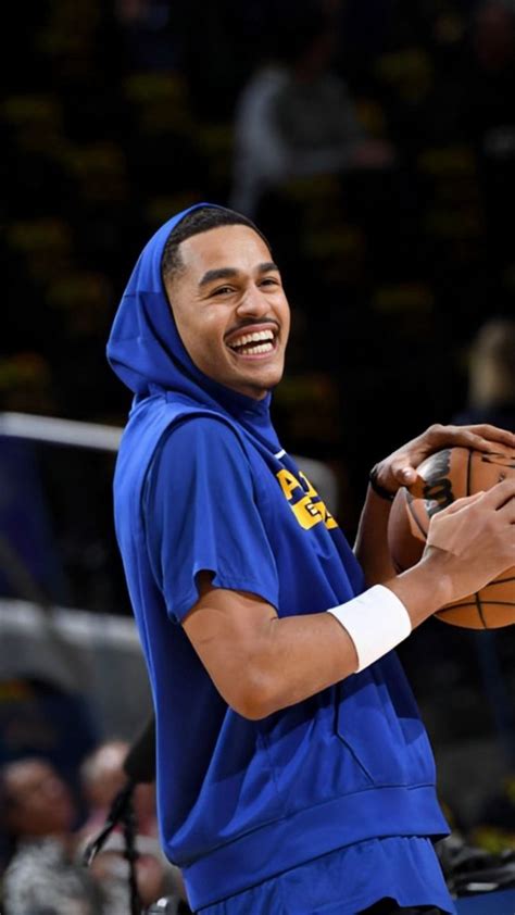 A Smiling Man Holding A Basketball In His Right Hand And Wearing A Blue