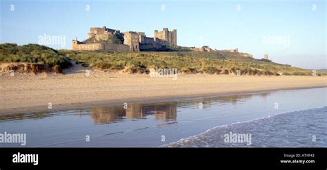 Historical Coastal Bamburgh Castle Landscape Reflection In Sandy Beach