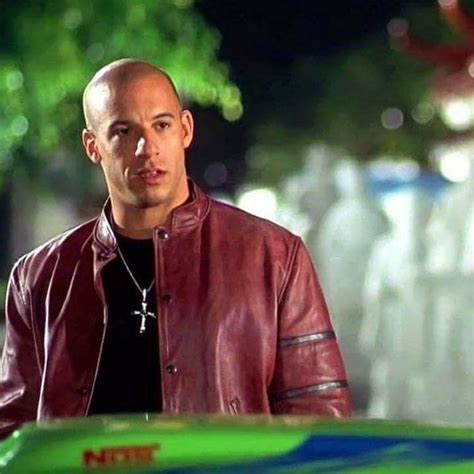 A Bald Man In A Red Leather Jacket Standing Next To A Green And Blue Car