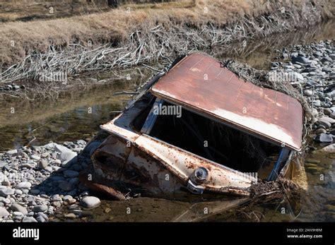 Rusted abandoned car half-submerged in water Stock Photo - Alamy