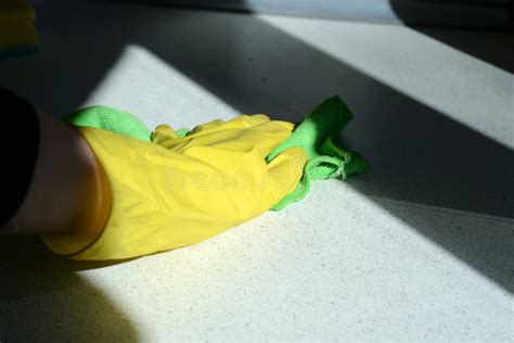 Hand In Yellow Rubber Glove Washing Kitchen Surface Lit By The Sun