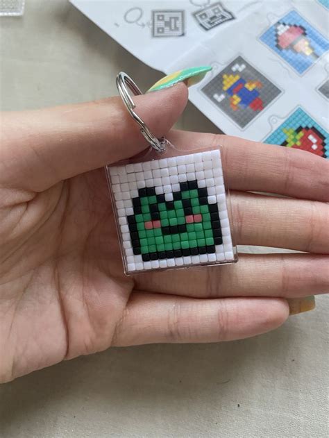 A Hand Holding A Keychain Made To Look Like An Old Video Game Character