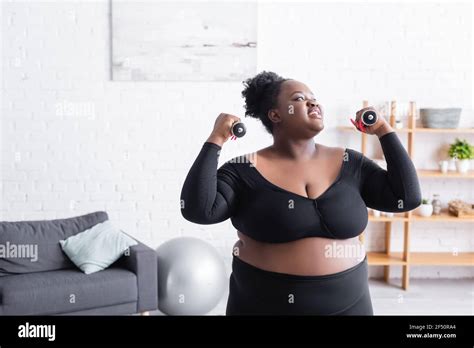 Smiling African American Plus Size Woman In Sportswear Exercising With