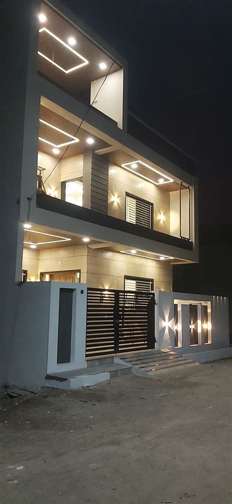 A Modern House Lit Up At Night With Lights On The Front And Side Of It