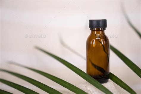 Blank Amber Glass Essential Oil Bottle On Tropical Leaf Background