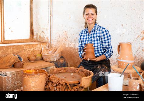 Portrait Of Adult Female Potter Working With Clay On Pottery Wheel In