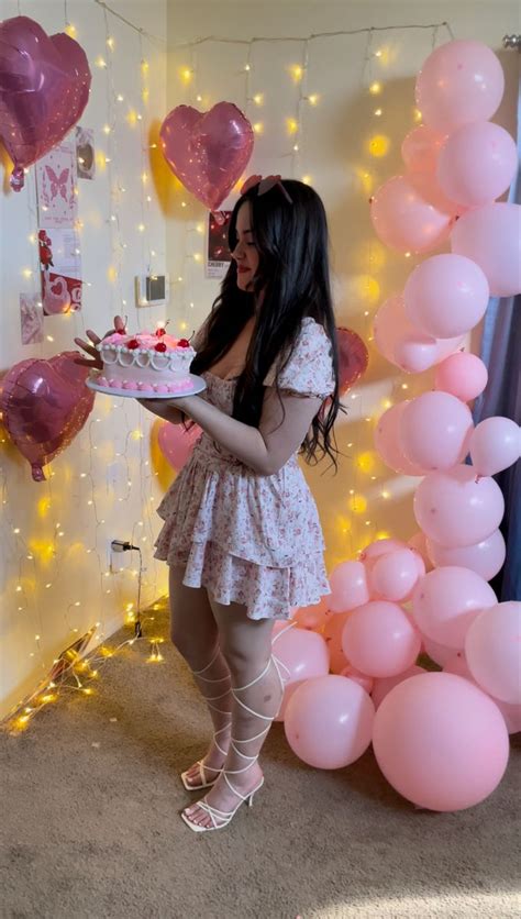 A Woman Holding A Cake In Front Of Balloons