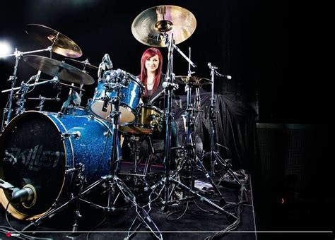 A Woman With Red Hair Is Playing The Drums In Front Of A Drum Set On Stage