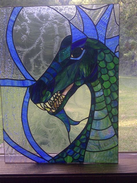 A Stained Glass Window With A Blue Dragon On Its Face And Green Grass In The Background