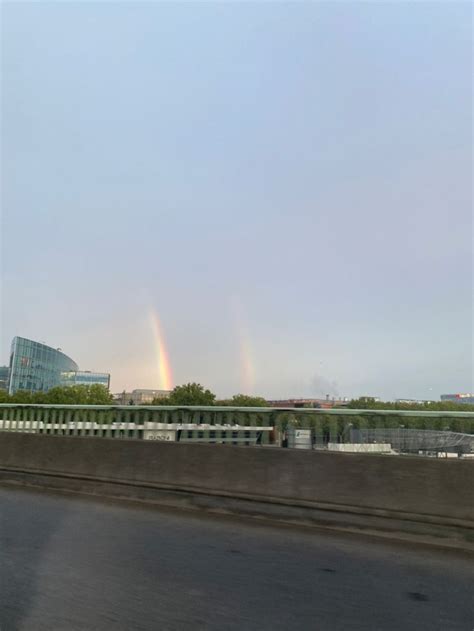 Two Rainbows Are Seen In The Sky Over A Highway