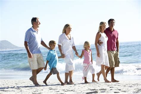 Família De Três Gerações Que Anda Ao Longo Da Praia De Sandy Imagem de