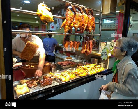 A Taiwanese Woman Looks At A Chef Carving Roast Duck At A Cantonese