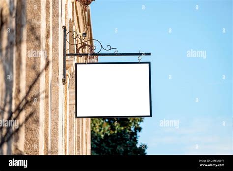 Blank Signboard Mockup Hanging On The Wall Of The Store In The Street