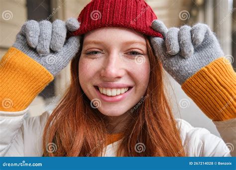 Headshot Of Happy Redhead Girl With Freckles Wears Red Hat And Gloves In Winter Walks Around