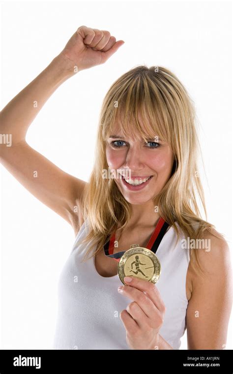 A Woman Holding A Gold Medal And Raising Her Fist In Celebration Stock