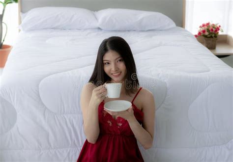 Beautiful Asian Girl Wearing Red Pajamas Sitting In The White Bedroom