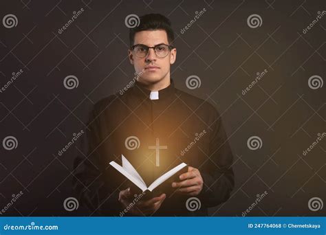 Sacerdote En La Sotana Sostiene La Biblia Con Luz Sagrada Sobre Fondo