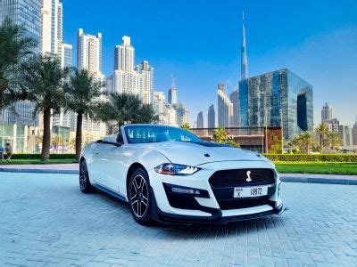 A White Sports Car Parked In Front Of A City Skyline