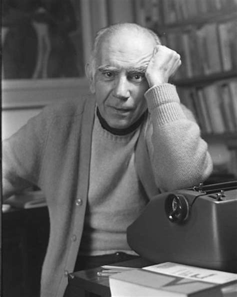 An Old Man Sitting At A Desk In Front Of A Typewriter With His Hand On