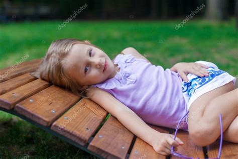 Petite Fille Mignonne Allongée Sur Une Chaise En Bois En Plein Air Dans