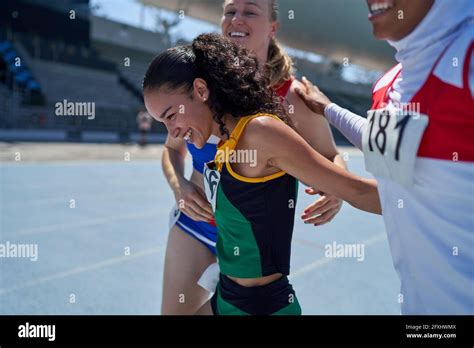 Happy Female Track And Field Athletes Celebrating On Track Stock Photo