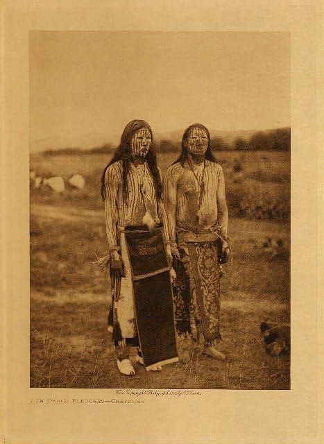 Two Native American Women Standing Next To Each Other In An Open Field