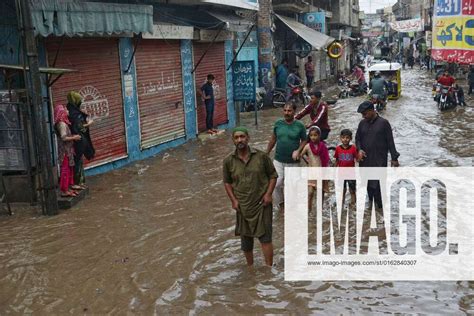 Pakistani Commuters Wade Through A Flooded Street At Baghban Pura Area