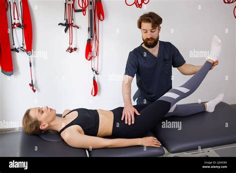 Professional Physiotherapist Lifting His Female Patients Leg Doctor Helps A Woman To