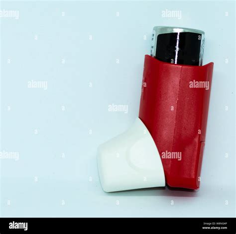 A red and white asthma rescue inhaler standing in front of a white ...