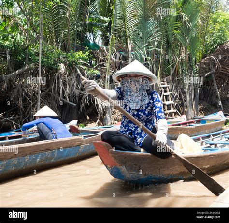 Vietnamese Woman Wearing A Conical Straw Hat Or Non La While Paddling A